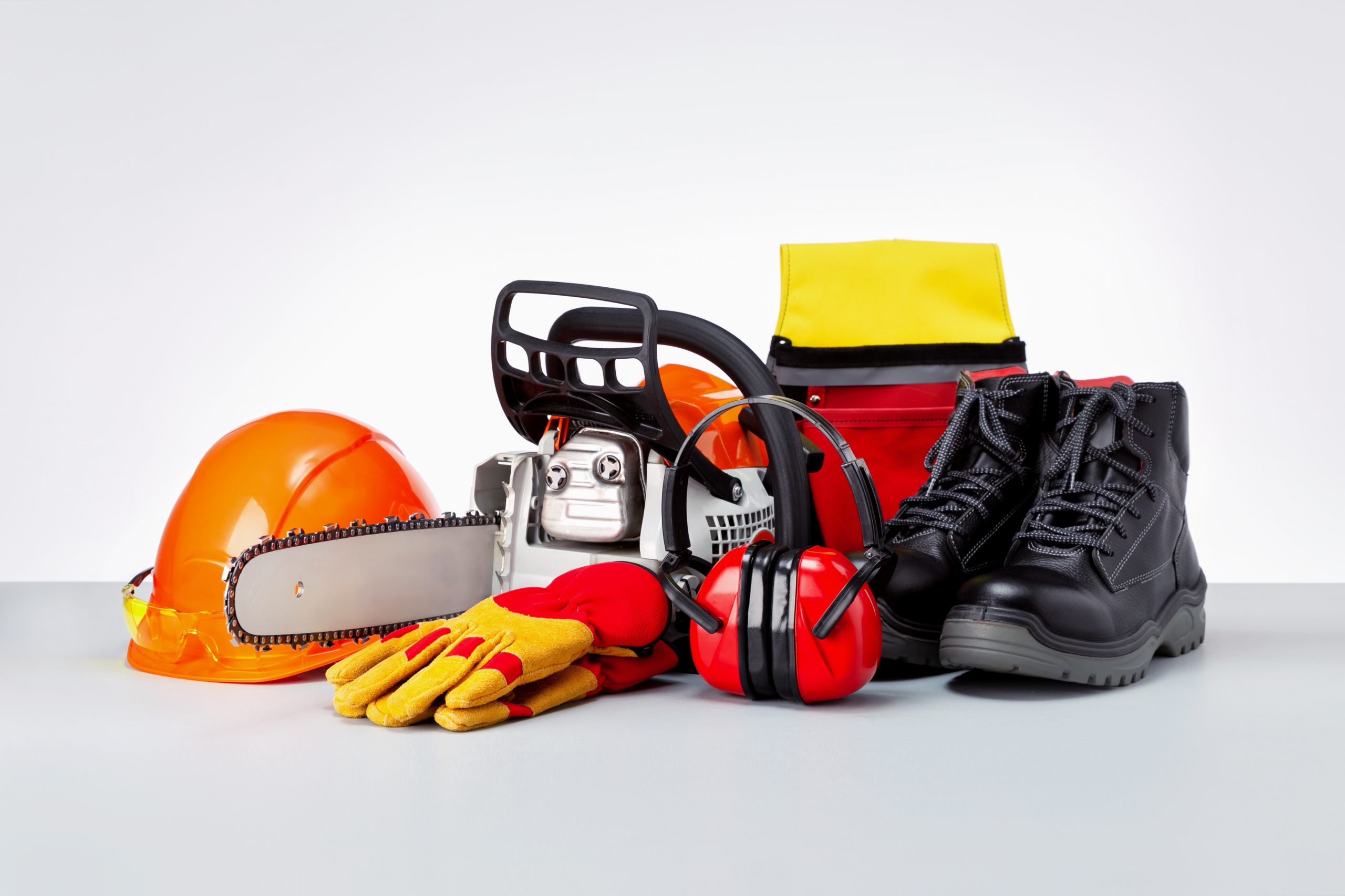 Chainsaw and protective clothes of lumberjack on grey surface.